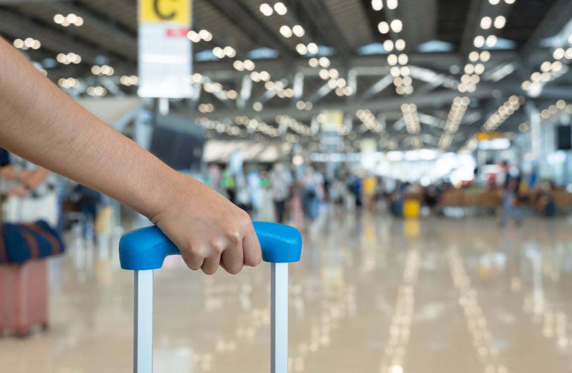 Woman Hand Holding Baggage Handle with Blurred Airport Terminal